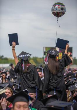 Graduates waving their graduation caps at commencement